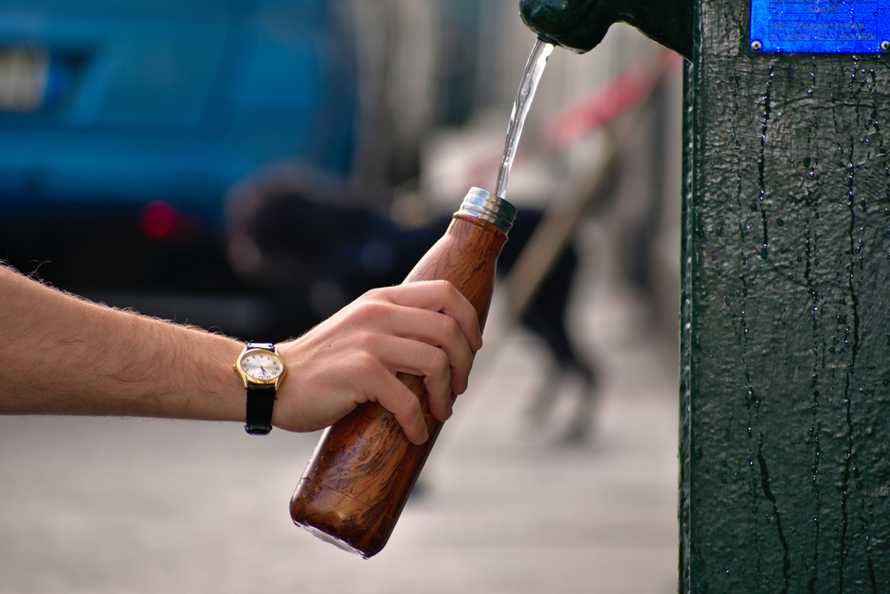 Person, die wiederverwendbare Wasserflasche füllt