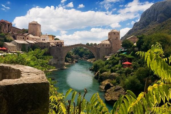Il vecchio ponte di Mostar, circondato da colline rigogliose
