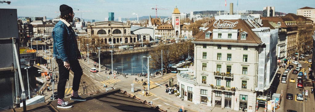 24_hours_in_zurich_-_man_looking_over_the_town_view_on_the_roof_in_zurich_switzerland_desktop