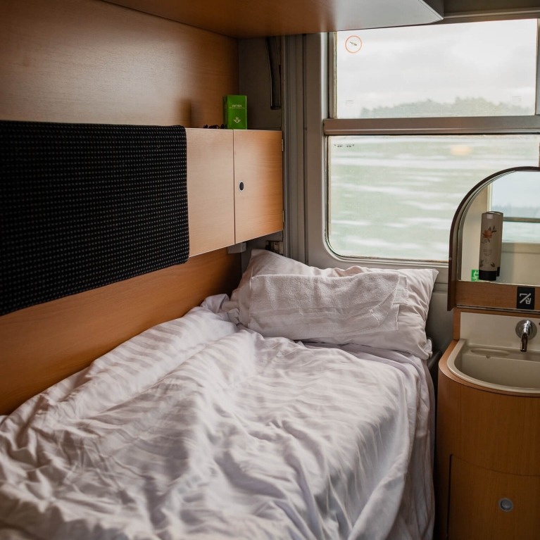 Un letto all'interno di un treno notturno, con vista sulla campagna svedese all'esterno