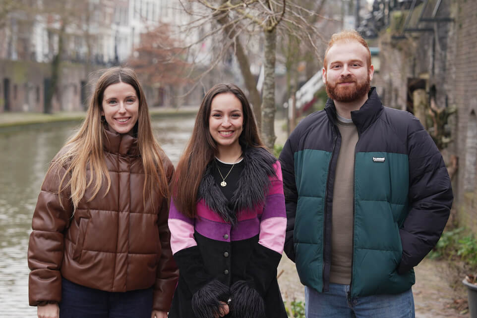 Two Eurail employees and a Utrecht local posing for a photo by the Oudegracht canal in Utrecht