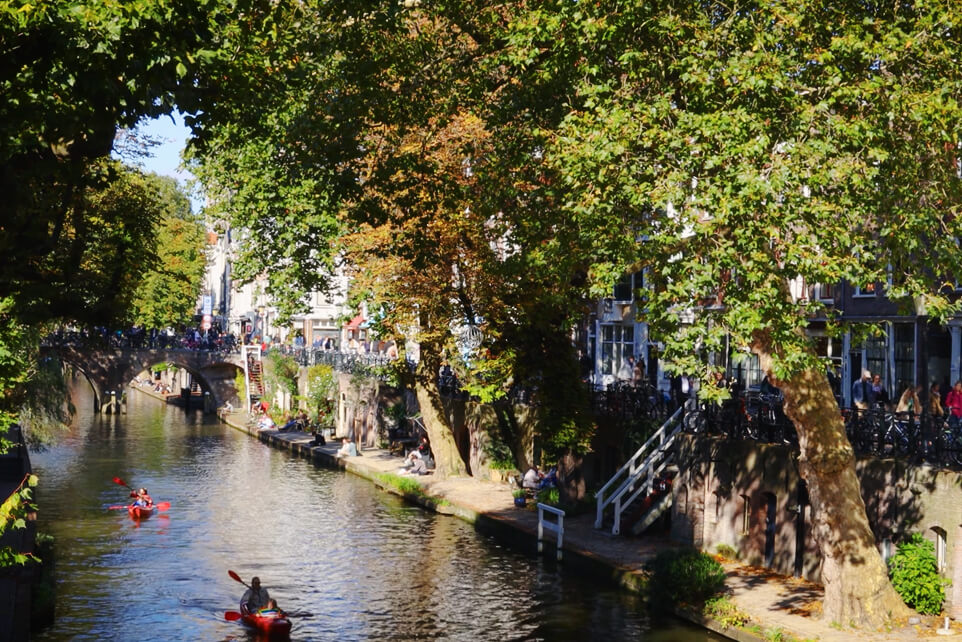 People kayaking through the Oudegracht canal in Utrecht on a sunny day