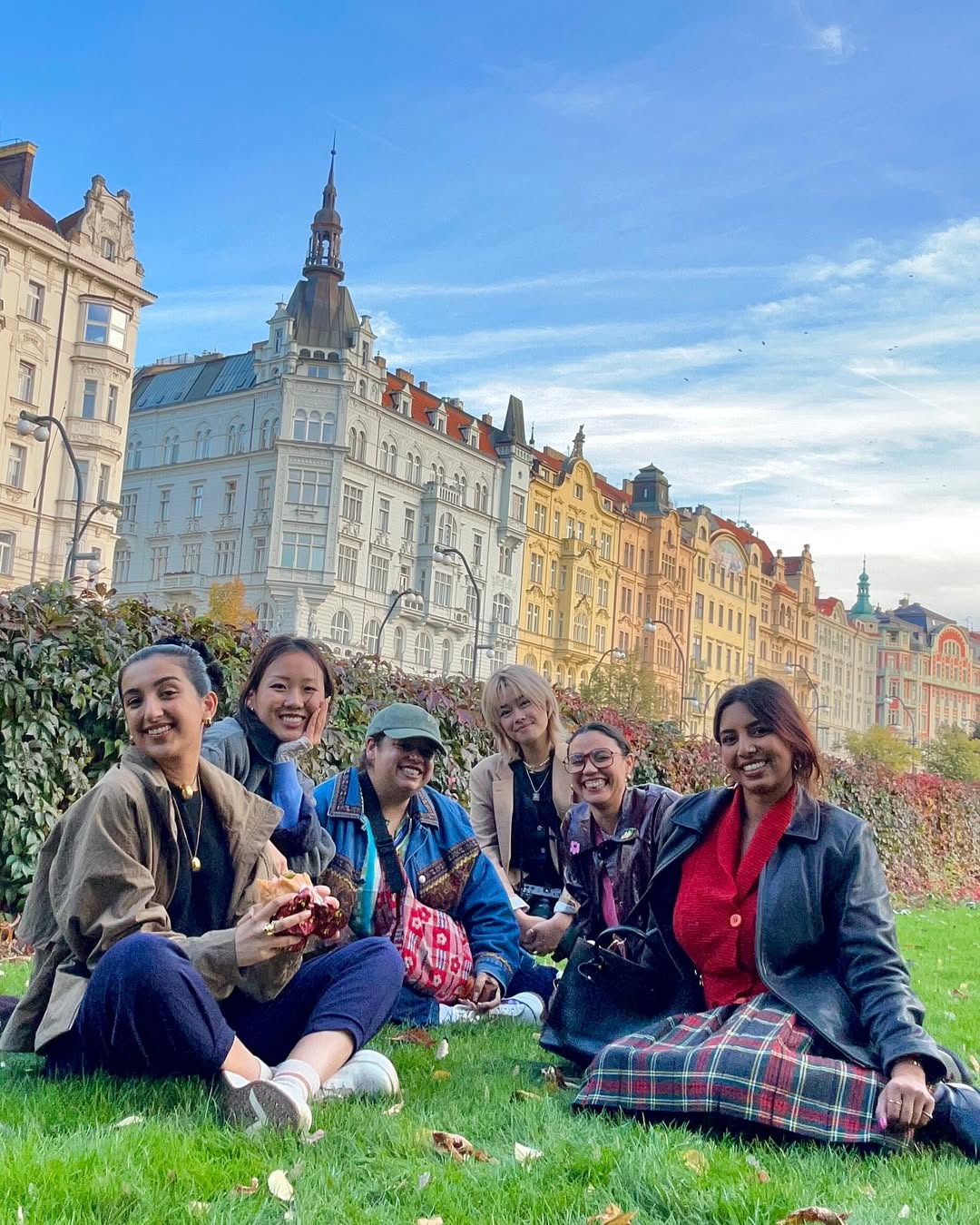 Six women seated in a park on a sunny day in Prague