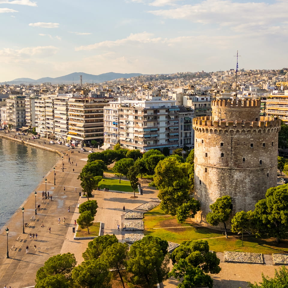 Aerial view of the White Tower in Thessaloniki, Greece, surrounded by lush greenery and the vibrant cityscape | What do to in Thessaloniki, Greece