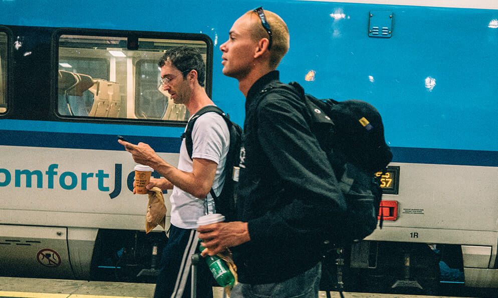 Two people walk alongside a train in a station