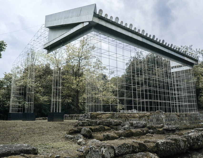 Ruines en pierre d'un ancien temple, avec des structures modernes et un toit partiel montrant à quoi ressemblait le temple avant qu'il ne tombe en ruine