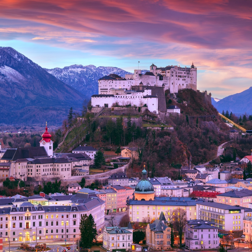 Vista aérea do castelo de Salzburgo, empoleirado em uma colina alta sobre a cidade, durante um pôr do sol rosa